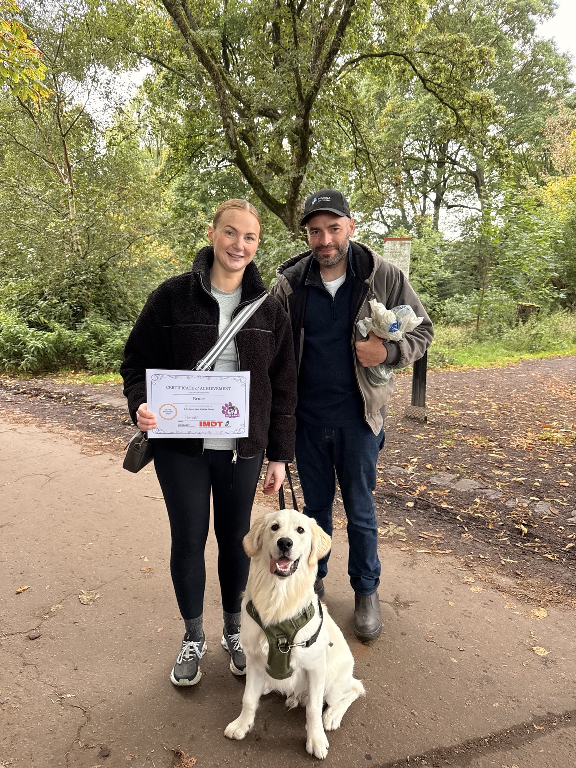 Bruce the golden retriever with his owners and training certificate